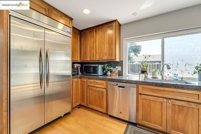 kitchen featuring stainless steel appliances, light hardwood / wood-style floors, sink, and decorative backsplash