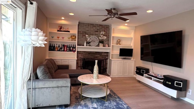 living room featuring ceiling fan, hardwood / wood-style flooring, a fireplace, and built in shelves