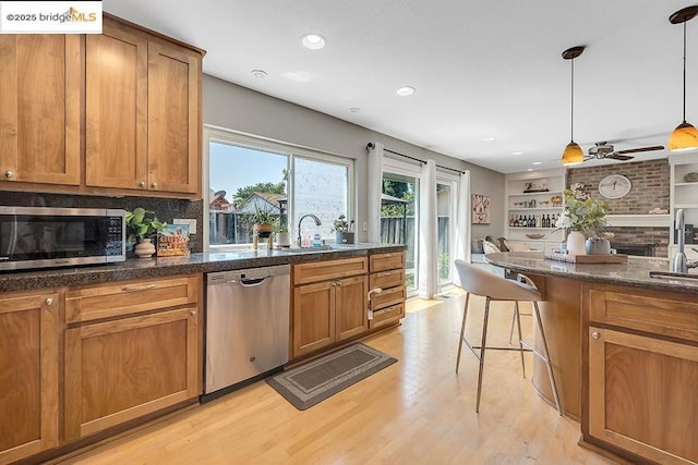 kitchen featuring sink, a breakfast bar area, decorative light fixtures, light wood-type flooring, and appliances with stainless steel finishes