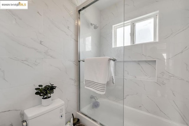 bathroom featuring enclosed tub / shower combo and toilet