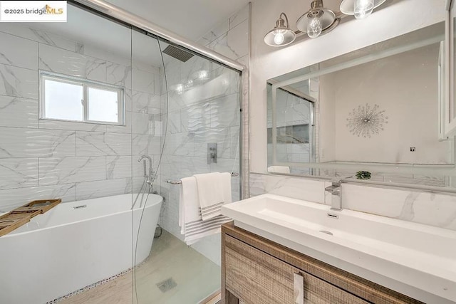 bathroom featuring vanity, shower with separate bathtub, and tile walls