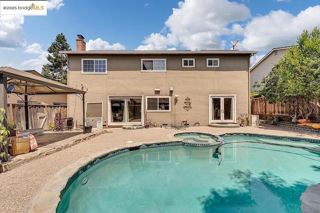 rear view of property with a swimming pool with hot tub, a gazebo, a patio, and french doors