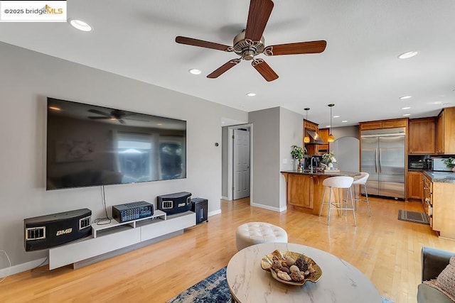 living room featuring sink, light hardwood / wood-style flooring, and ceiling fan