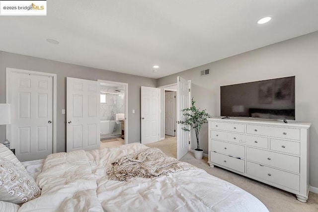 bedroom with connected bathroom and light carpet