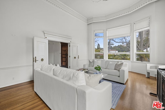 living room with hardwood / wood-style flooring, crown molding, and a towering ceiling