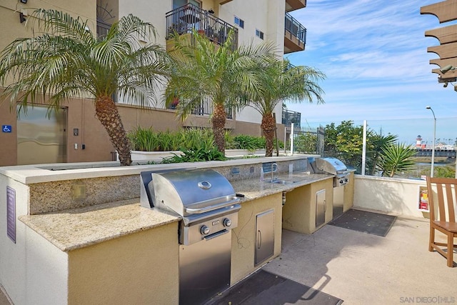 view of patio featuring an outdoor kitchen, area for grilling, and sink