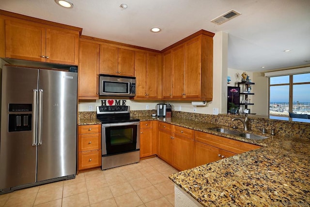 kitchen with sink, light tile patterned floors, dark stone counters, kitchen peninsula, and stainless steel appliances