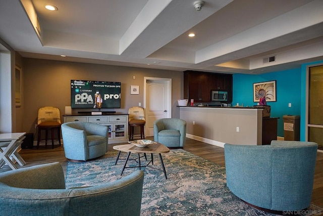 living room featuring dark hardwood / wood-style flooring and a raised ceiling