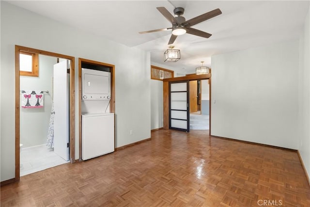 empty room with parquet flooring, stacked washer and dryer, and ceiling fan