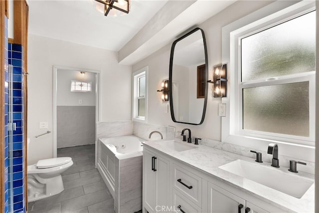 bathroom with a relaxing tiled tub, tile patterned floors, vanity, and toilet