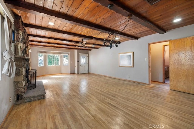 unfurnished living room featuring baseboards, wooden ceiling, beamed ceiling, a stone fireplace, and light wood-type flooring