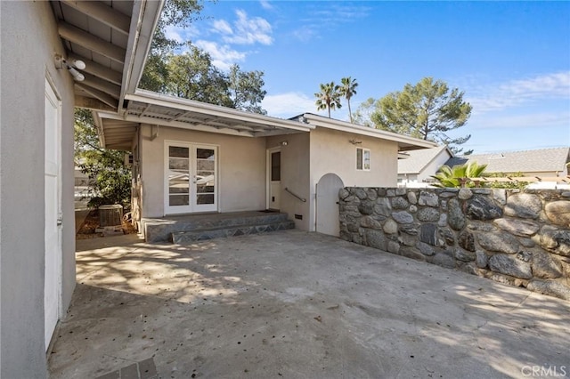 exterior space featuring french doors, a patio, stucco siding, a gate, and cooling unit