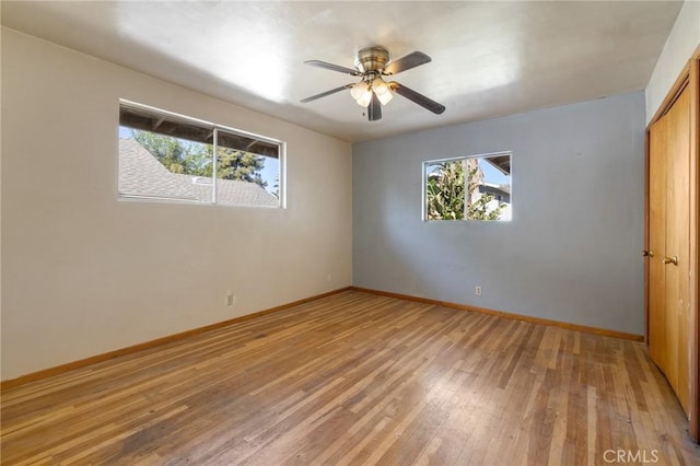 spare room featuring a ceiling fan, baseboards, and wood finished floors