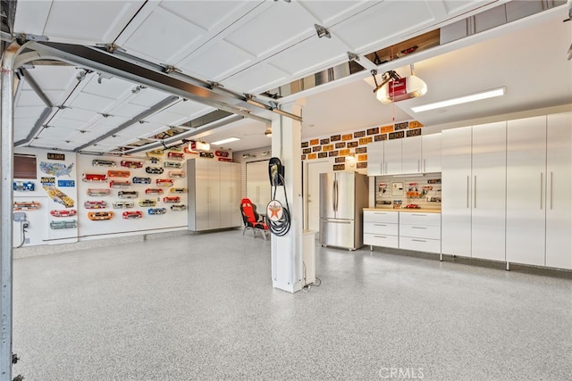 garage featuring stainless steel refrigerator and a garage door opener