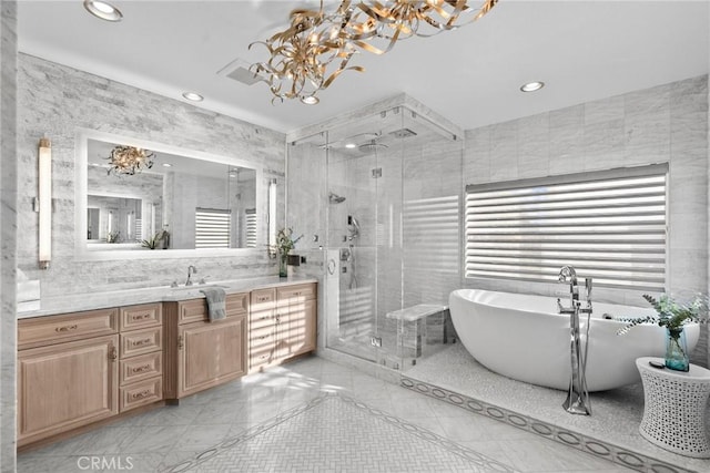 bathroom with vanity, shower with separate bathtub, a chandelier, and tile walls