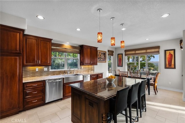 kitchen featuring pendant lighting, dishwasher, sink, dark stone countertops, and a center island