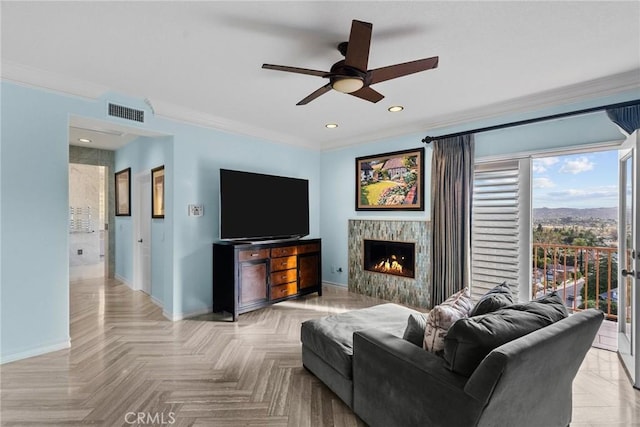 living room with light parquet floors, ornamental molding, ceiling fan, and a tile fireplace