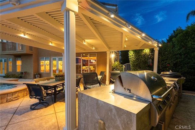 patio at twilight featuring an outdoor kitchen, grilling area, and a pergola