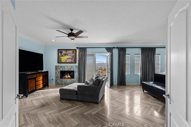 living room featuring crown molding, ceiling fan, light parquet flooring, and a fireplace