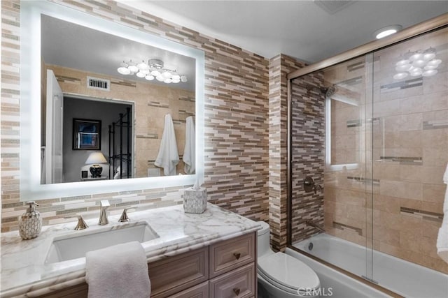 full bathroom with enclosed tub / shower combo, tile walls, backsplash, vanity, and toilet