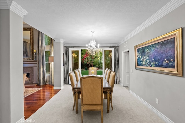 carpeted dining space with a textured ceiling, ornamental molding, and a chandelier