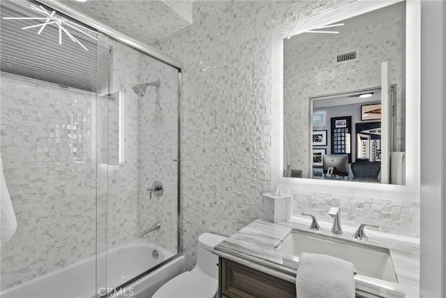 full bathroom with tasteful backsplash, vanity, toilet, and combined bath / shower with glass door