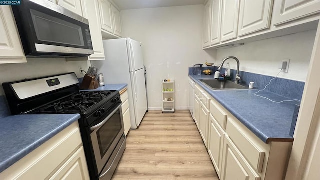 kitchen featuring stainless steel appliances, sink, white cabinets, and light hardwood / wood-style floors