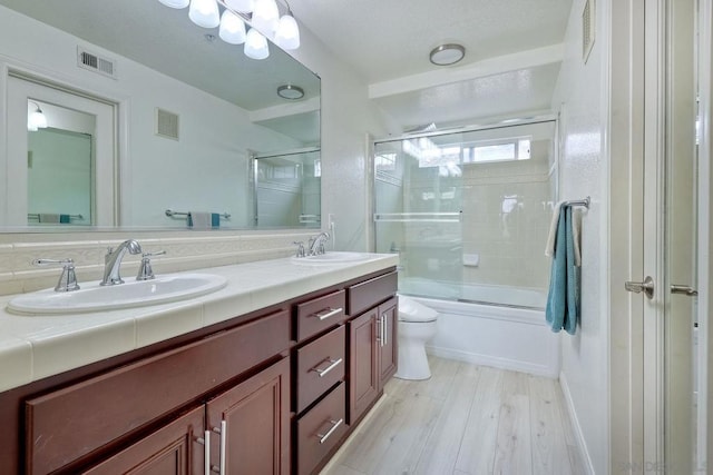 full bathroom featuring bath / shower combo with glass door, vanity, toilet, and hardwood / wood-style floors