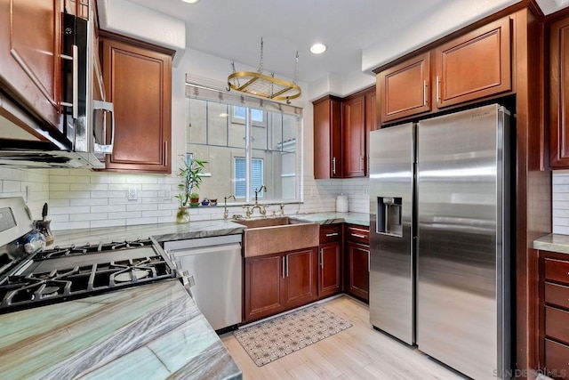 kitchen with appliances with stainless steel finishes, light stone countertops, sink, and backsplash