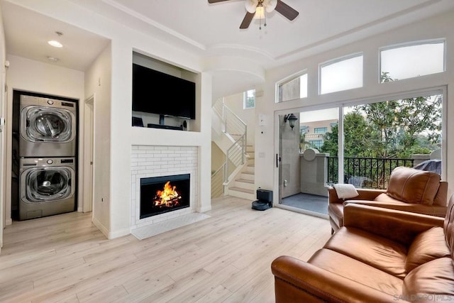 living room with light wood-type flooring, ceiling fan, and stacked washer / dryer