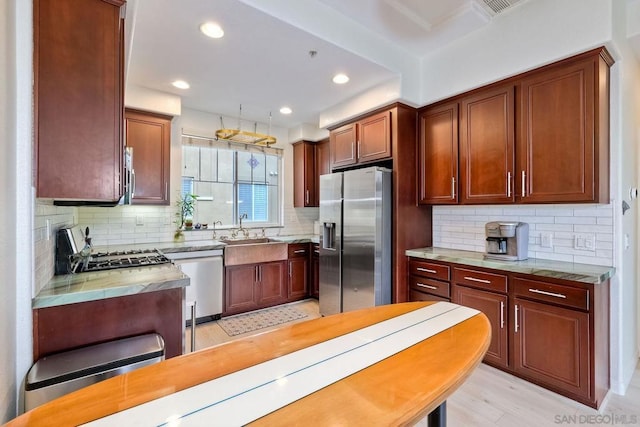 kitchen with sink, decorative backsplash, light hardwood / wood-style floors, light stone counters, and stainless steel appliances