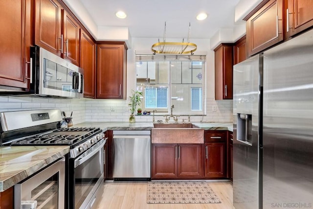 kitchen with sink, stainless steel appliances, light stone counters, tasteful backsplash, and beverage cooler