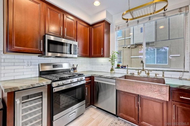 kitchen with sink, appliances with stainless steel finishes, beverage cooler, light stone countertops, and backsplash