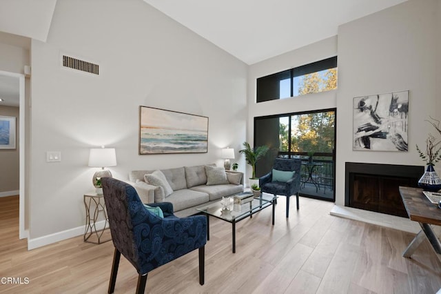 living room featuring high vaulted ceiling and light hardwood / wood-style floors