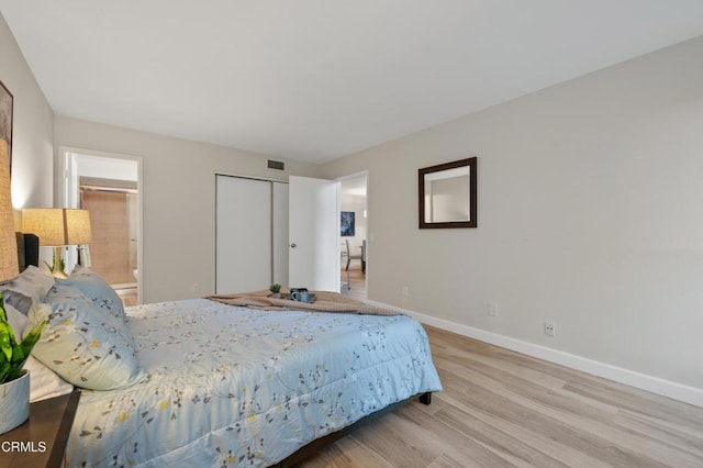 bedroom with connected bathroom, a closet, and light wood-type flooring