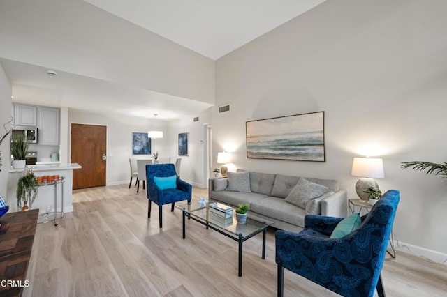 living room with a high ceiling and light hardwood / wood-style flooring