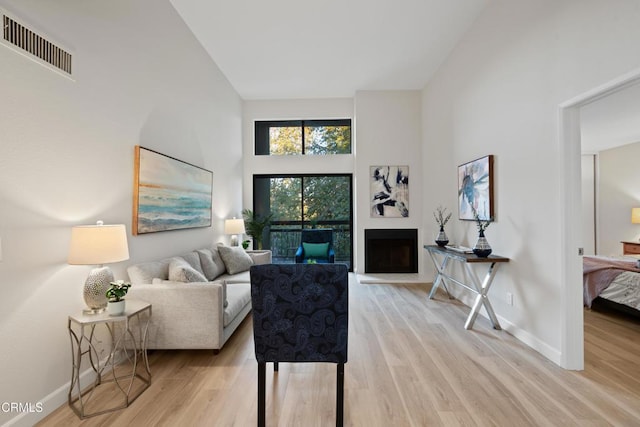 living room with light hardwood / wood-style floors and a high ceiling