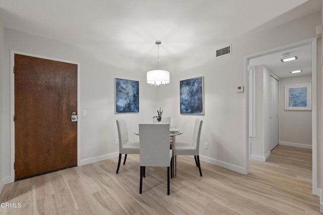 dining space with a chandelier and light wood-type flooring