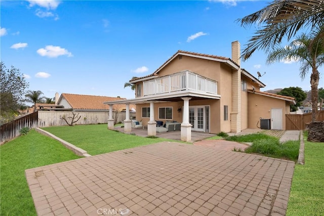 rear view of house with a patio, a balcony, a lawn, and a fenced backyard