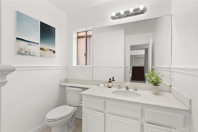 bathroom featuring baseboards, toilet, and vanity