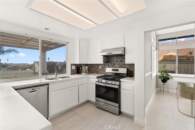 kitchen with a sink, stainless steel appliances, under cabinet range hood, white cabinetry, and tasteful backsplash