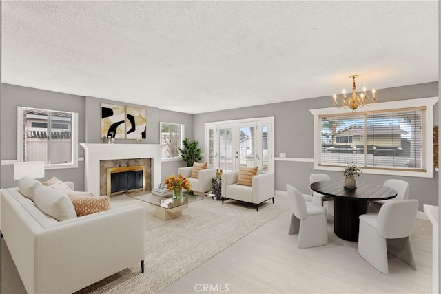 living room featuring a premium fireplace, plenty of natural light, a textured ceiling, and an inviting chandelier