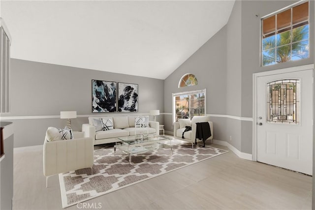 living room with high vaulted ceiling and baseboards