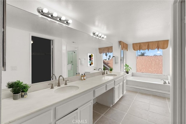 bathroom featuring tile patterned flooring, double vanity, a bath, and a sink