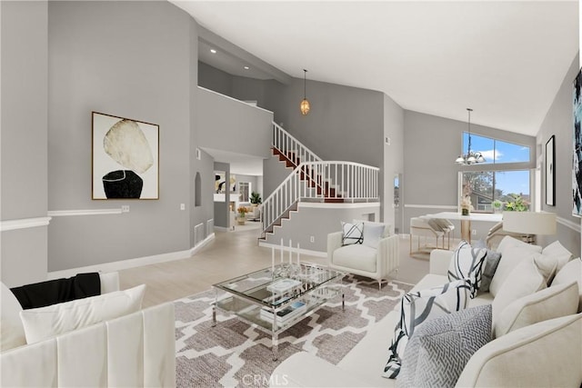 living area featuring stairway, baseboards, high vaulted ceiling, and a notable chandelier