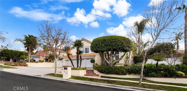 view of property hidden behind natural elements featuring stucco siding, driveway, a tile roof, and a garage