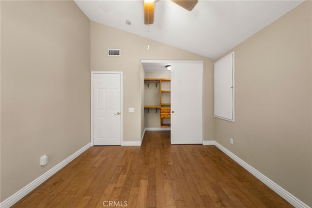 unfurnished bedroom featuring wood-type flooring, lofted ceiling, a spacious closet, ceiling fan, and a closet