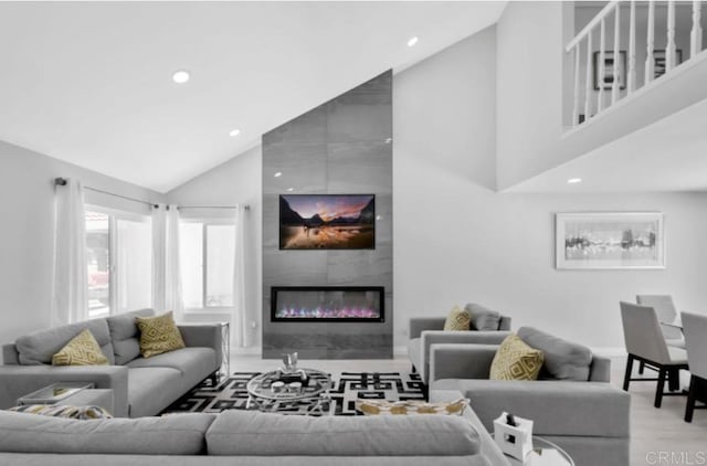 living room featuring a large fireplace, high vaulted ceiling, and light hardwood / wood-style floors