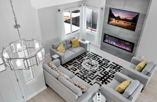 living room with a premium fireplace, a chandelier, and light hardwood / wood-style floors