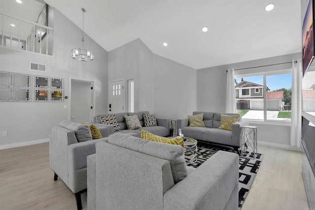 living room with a notable chandelier, light hardwood / wood-style flooring, and high vaulted ceiling